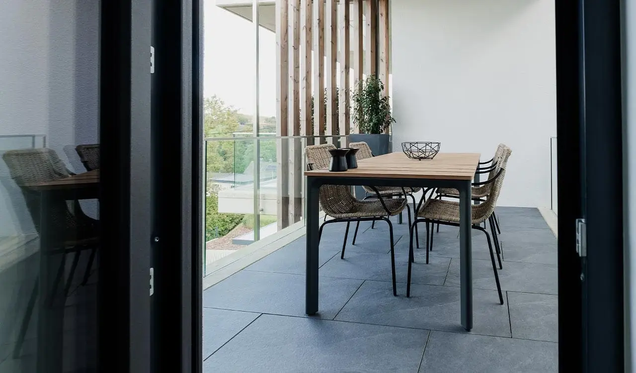 Balkon zwischen Holzlamellen mit Esstisch und Blick in die Landschaft