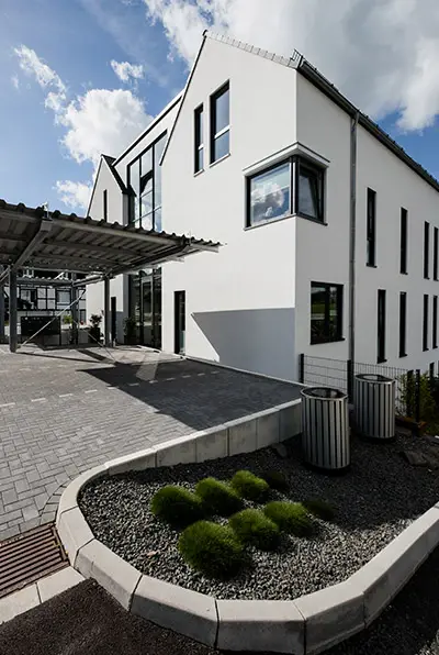 Eingangsbereich mit Pflanzinsel vor der weißen Putzfassade