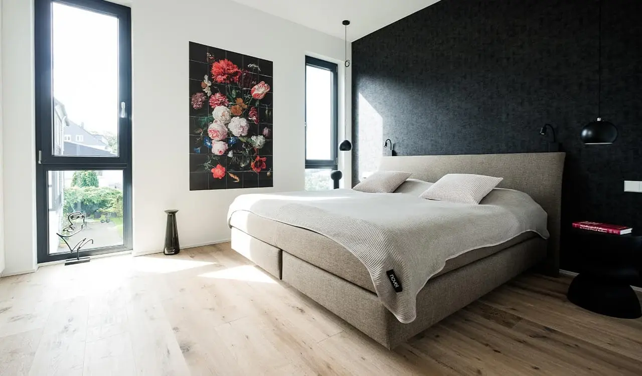 Schlafzimmer mit Eichenparkett, dunkler Wandfläche und Blumenstillleben