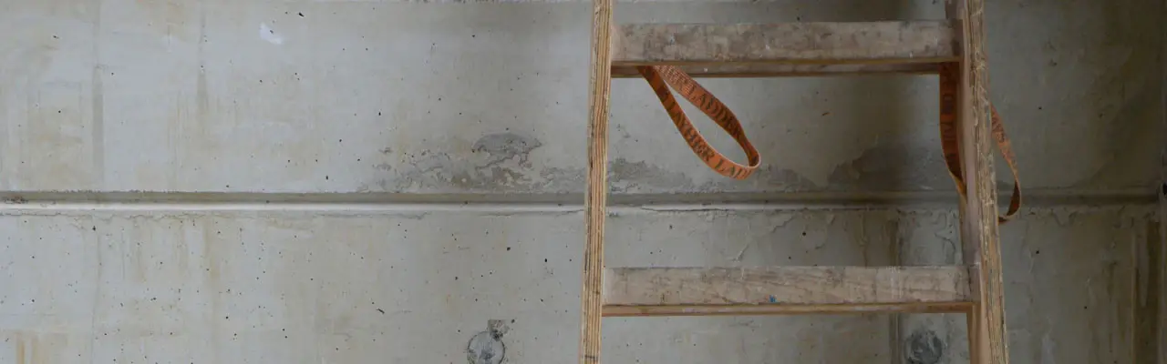 Holzleiter an einer Sichtbetonwand