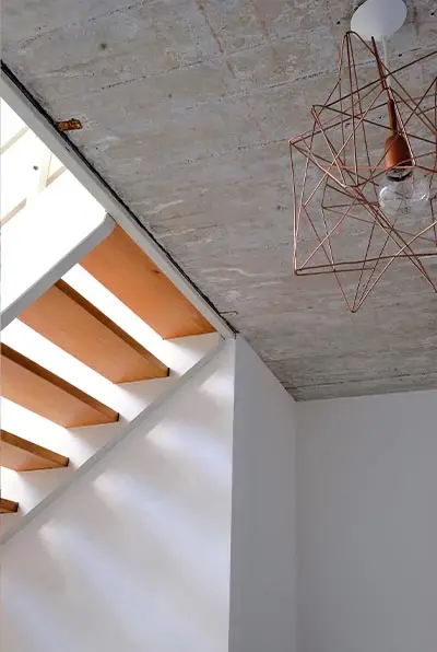 Treppenauge mit Holzstufen und Kupferleuchte