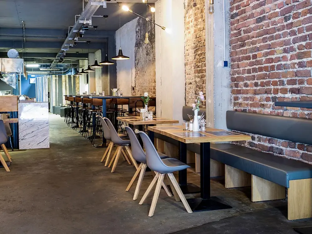 Gastraum des Restaurants Meat me mit Sitzbänken, Holztischen und Backsteinwand