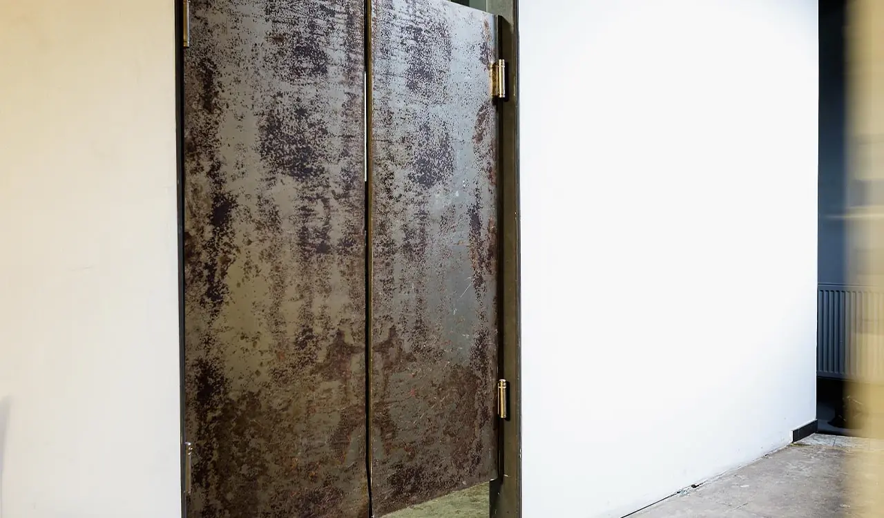 Tür mit Rostpatina neben weißer Wand