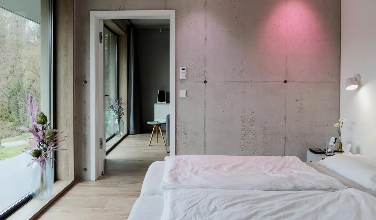 Schlafzimmer mit Sichtbetonwand und raumhoher Schiebetür