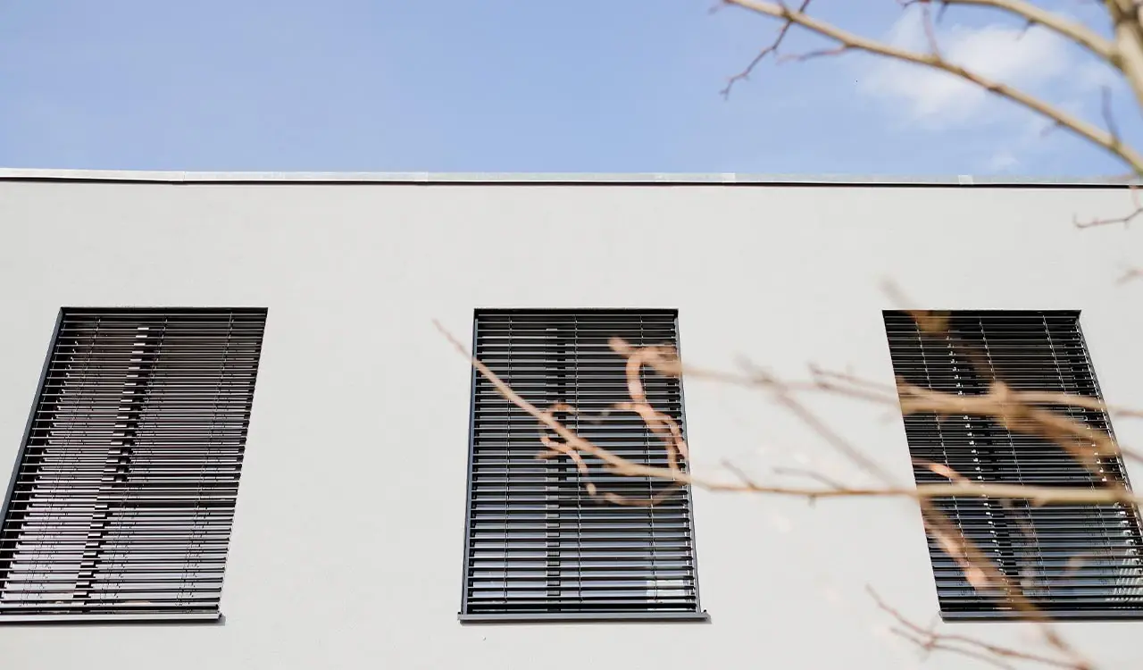 Weiße Fassade mit dunklen Lamellenläden