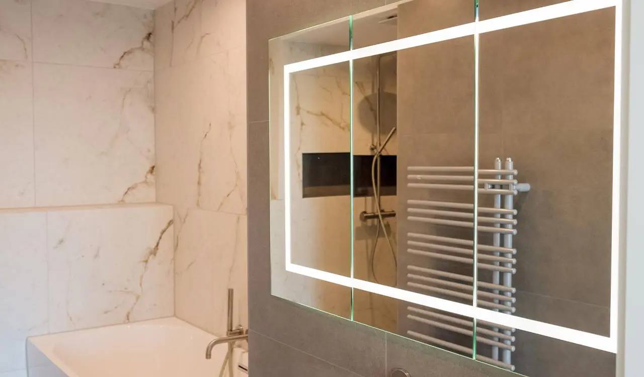 Bad mit geäderten Wandflächen und beleuchtetem Spiegel