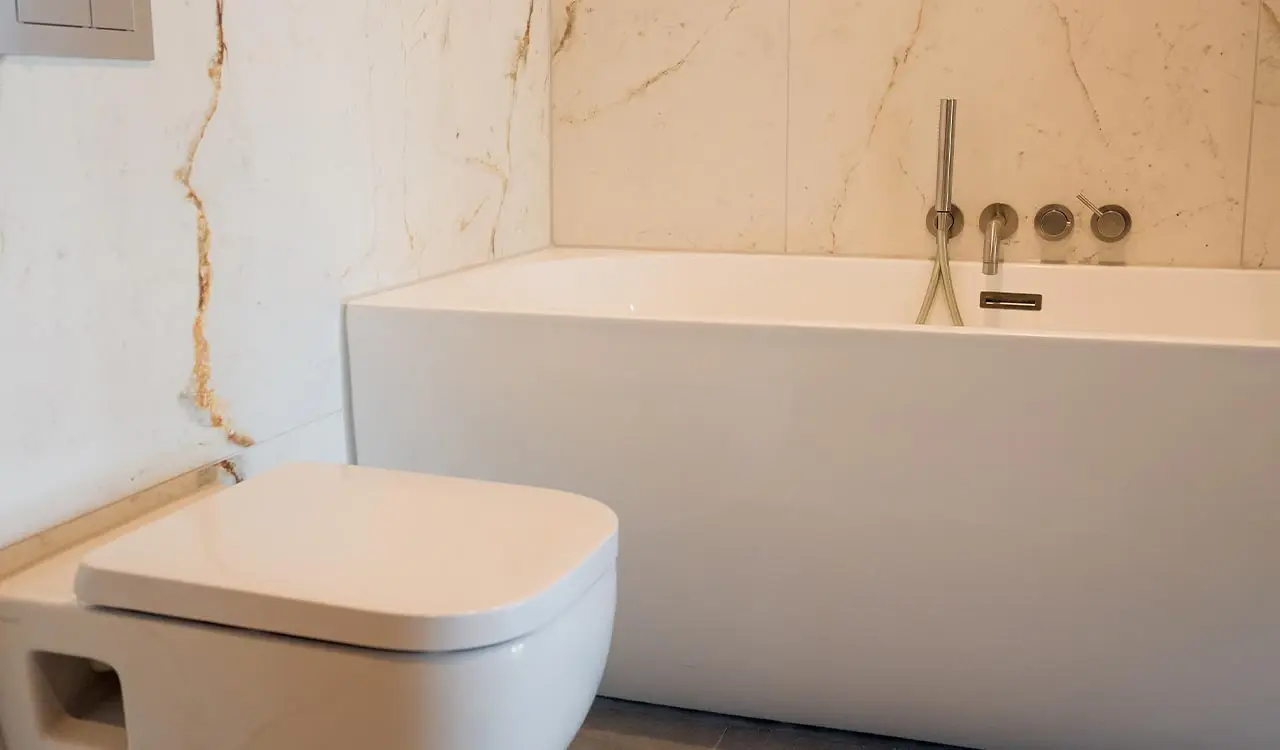 Freistehende Badewanne vor geäderter Wandfläche