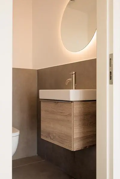 Gäste-WC mit rundem Spiegel und Holzunterschrank